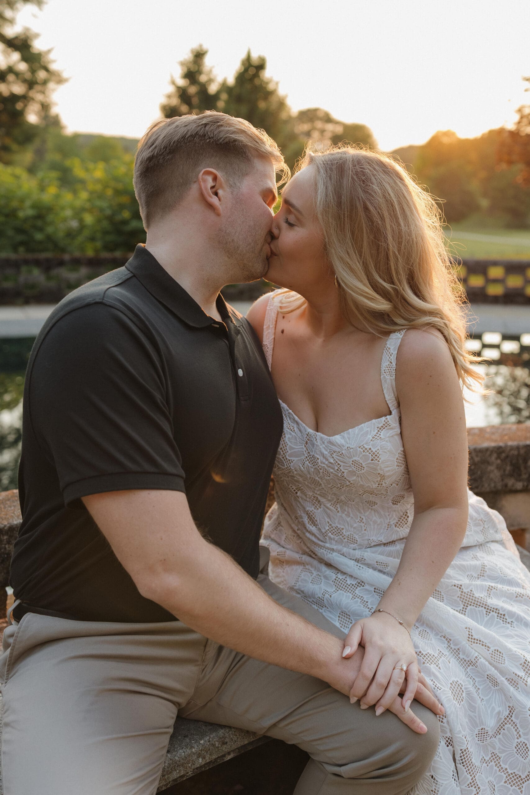 Couple kissing during golden hour engagement session at Felt Estate in Michigan with warm sunset light and natural candid moment