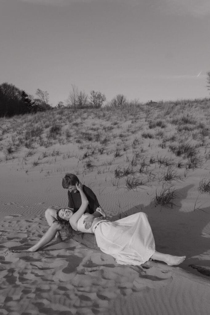 Couple cuddling on the beach during a couples session at Saugatuck Dunes State Park in Michigan