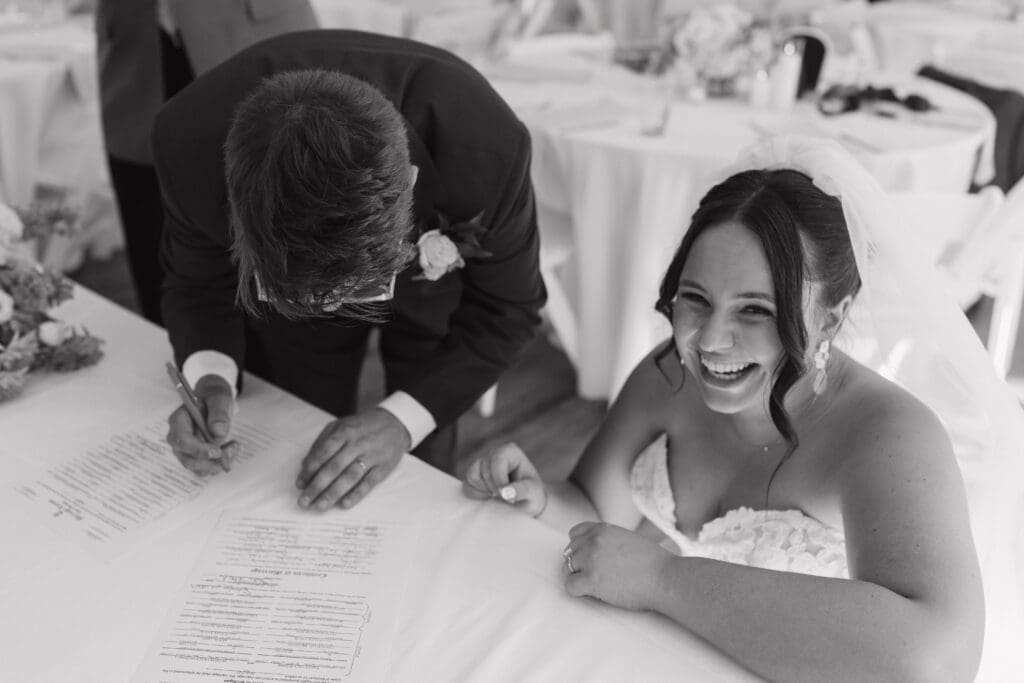 Couple signing their marriage license during a wedding reception at Grand Rapids Yacht Club in Michigan