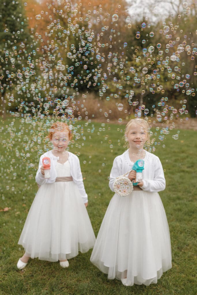 Flower girls blowing bubbles during an outdoor wedding at Bay Pointe Woods in Shelbyville, Michigan