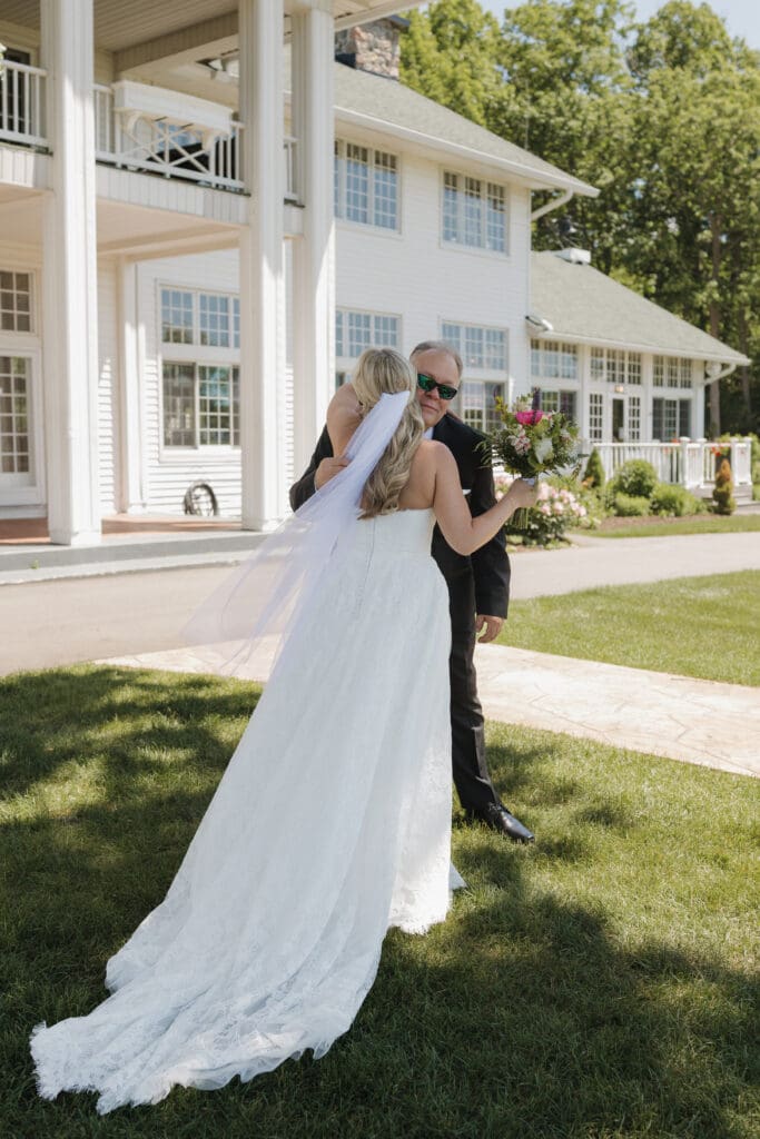 Bride hugging her father during a candid moment outside Walden Woods in Michigan.