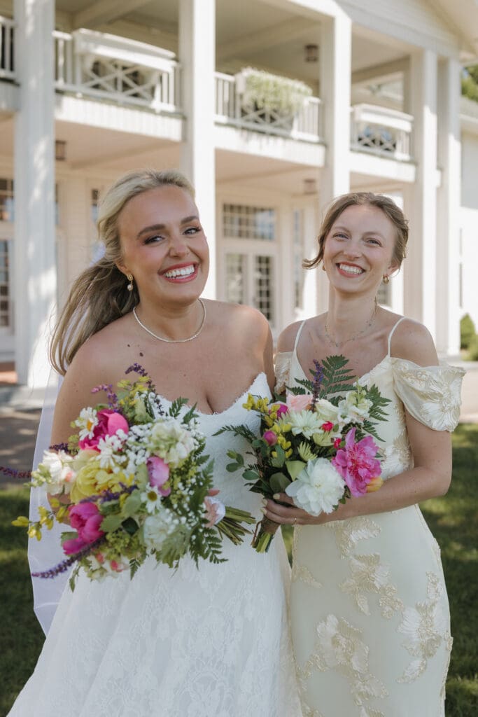 Bride and bridesmaid laughing together during bridal party portraits at a Walden Woods wedding in Michigan. 