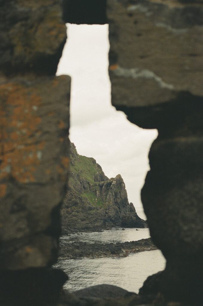 Rocky coastline framed by ancient stone ruins along the Northern Ireland coast, captured on 35mm film near a breathtaking destination elopement location.