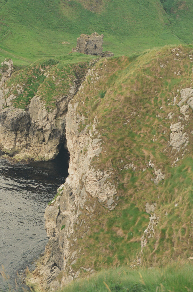 Rugged limestone cliffs and the ruins of Kinbane Castle overlooking the Atlantic Ocean on Northern Ireland's Causeway Coast, photographed on 35mm film beneath an overcast sky.
