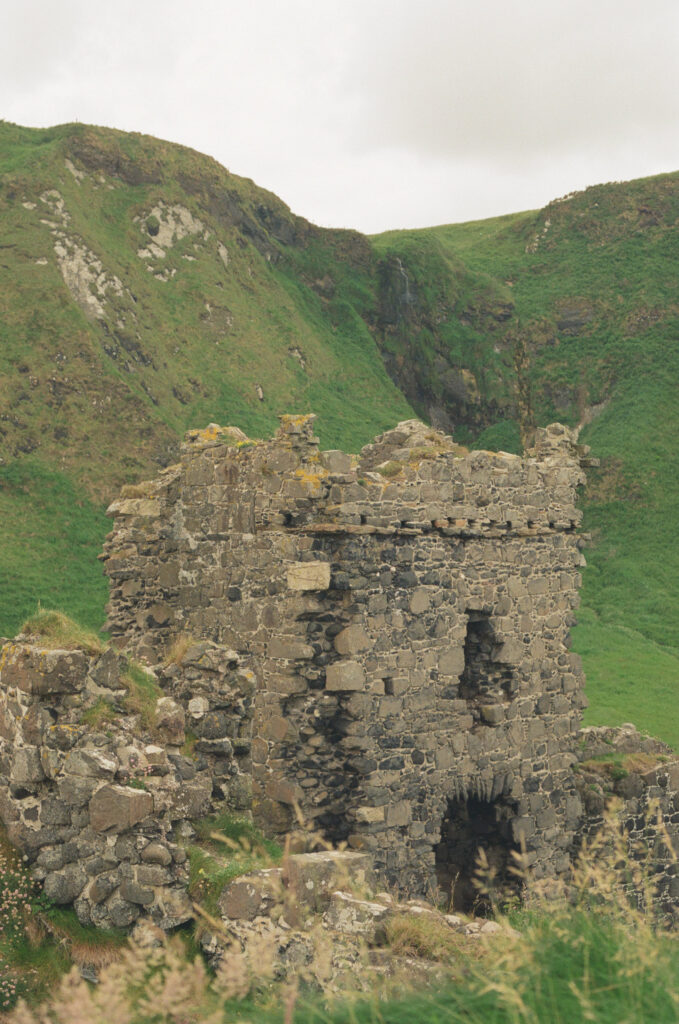 Ancient castle ruins perched on lush green cliffs overlooking the sea in Northern Ireland, an iconic destination elopement location.