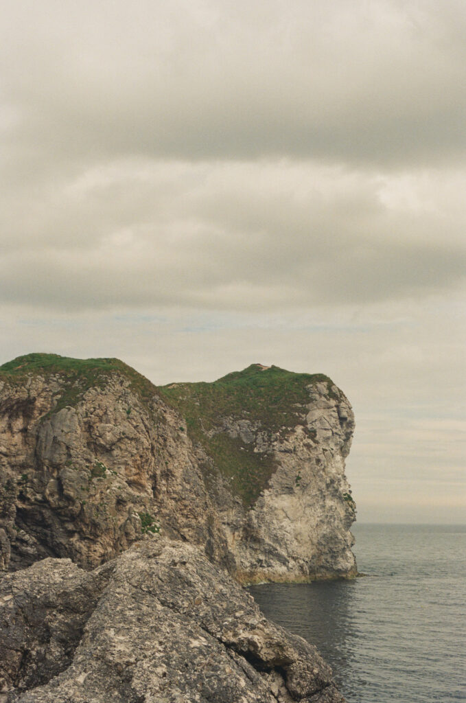 Dramatic limestone cliffs overlooking the sea at Kinbane Castle on the Causeway Coast in Northern Ireland, photographed on 35mm film beneath an overcast sky.