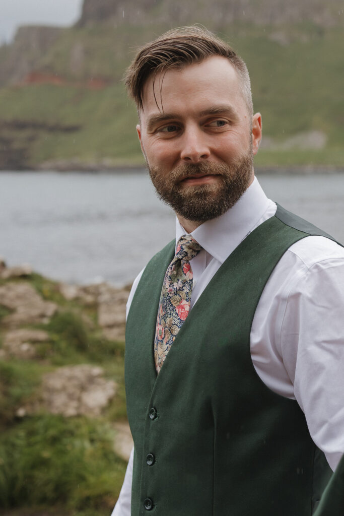 Portrait of a groom in a green suit overlooking the coastline during his Giant's Causeway elopement on the Causeway Coast of Northern Ireland.